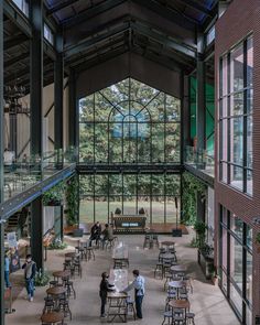 the inside of a building with people walking around and tables in front of them,