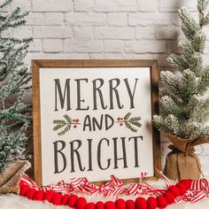 a sign that says merry and bright next to some christmas tree branches with pom - poms