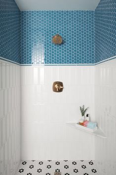 a bathroom with blue and white tiles on the walls, shower head and shelf in the corner