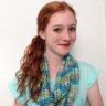 a young woman with red hair wearing a blue shirt and scarf, posing for the camera