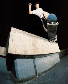 a man riding a skateboard up the side of a cement wall on top of a ramp