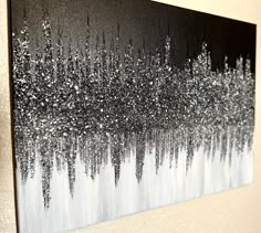 a black and white painting with silver glitters on it's edges is hanging on a wall