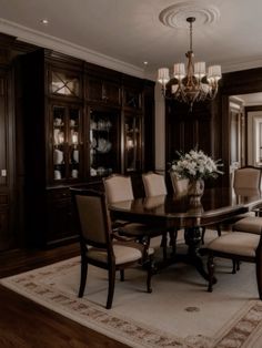 a formal dining room table and chairs with chandelier in the background on an area rug