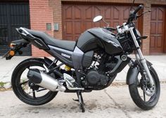 a black motorcycle parked in front of a brick building