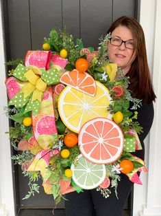 a woman holding a wreath made out of fruit