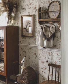 a room with floral wallpaper and wooden furniture in the corner next to a mirror