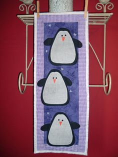 two penguins on a purple and white towel hanging from a metal rack against a red wall