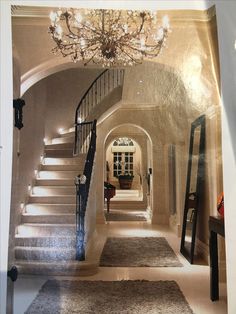 a hallway with stairs and chandelier in it