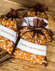 three bags filled with peanuts sitting on top of a wooden table next to each other