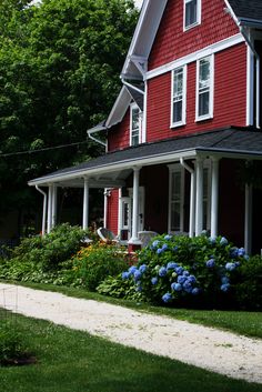 a red house with blue flowers in the front yard