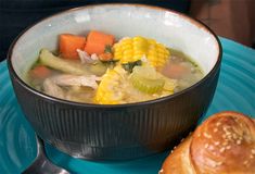 a bowl filled with soup next to a roll on top of a blue tablecloth