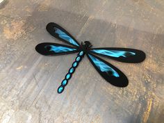 a blue and black dragonfly sitting on top of a table