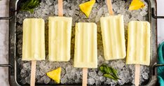 four popsicles on top of ice with pineapple slices and mint leaves in them