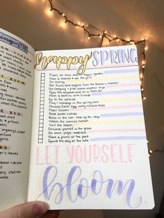 a hand holding an open planner with the words happy spring written on it