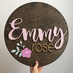 a person holding up a wooden sign that says,'emmy rose '