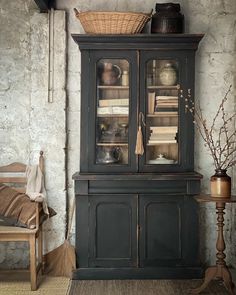 an old fashioned china cabinet with glass doors and shelves on the top, next to a wooden chair