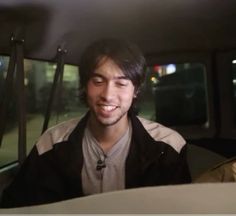 a young man sitting in the back seat of a car with his eyes closed and smiling