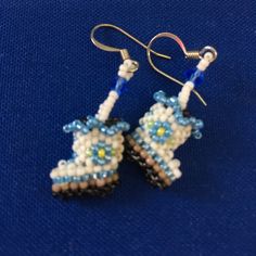 beaded earrings with blue and white beads are on a blue surface, one is dangling from the earwires