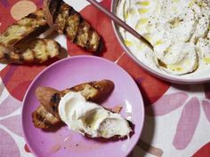 a plate with some food on it next to a bowl of yogurt and grilled bananas