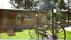 an old wooden wagon sitting in front of a small building with a sign on it