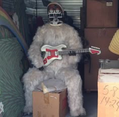 a large stuffed animal with a guitar sitting on top of a box