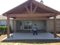 a man standing in front of a house under a wooden roof