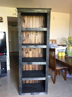 an old wooden bookcase sitting in the middle of a room next to a table