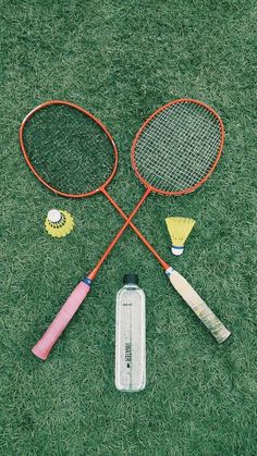 three tennis rackets and two badminton balls on the grass