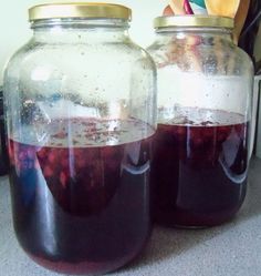 two jars filled with liquid sitting on top of a counter