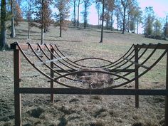 an old rusted metal bed frame sitting in the middle of a field with trees