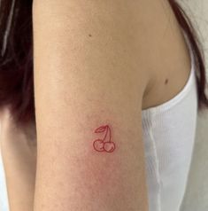 a woman's arm with a small red tattoo on the left side of her arm