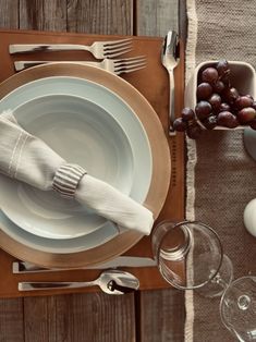 the table is set with white dishes, silverware and napkins for two people