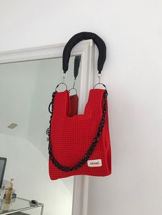 a red purse hanging from the side of a door with a black chain attached to it