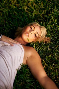 a woman laying in the grass with her eyes closed