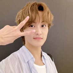 a young man holding his hand up in front of his face and making a peace sign