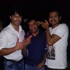 three men standing next to each other posing for the camera with their hands in the air