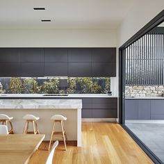 a kitchen with wooden floors and white counter tops next to an open dining room area