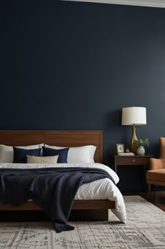 a bedroom with dark blue walls and white bedding, two chairs and a rug