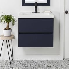 a white sink sitting under a mirror next to a potted plant