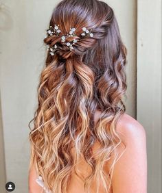 the back of a woman's head with wavy hair and flowers in her hair