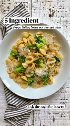 a white bowl filled with pasta and broccoli on top of a wooden table