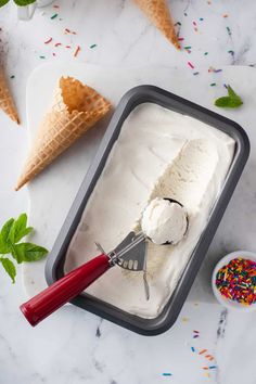 two scoops of ice cream and sprinkles on a marble counter top