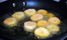 bananas frying in a pan on top of a stove burner with oil over them