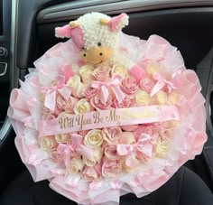 a teddy bear sitting on top of a bouquet of roses in the back seat of a car