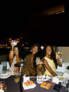 three women sitting at a table holding wine glasses