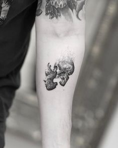 a man's arm with a skull and two skulls tattoo on the left forearm