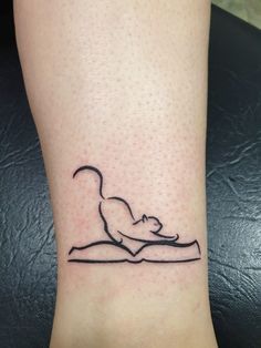 a small tattoo on the foot of a person with a cat sitting on top of a book