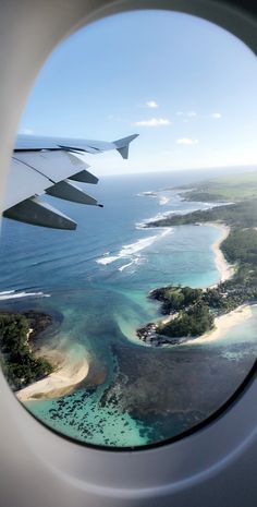 an airplane window looking out at the ocean and landforms in the water from above