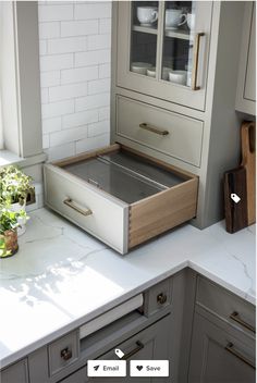 an open drawer in the middle of a kitchen counter top next to a potted plant