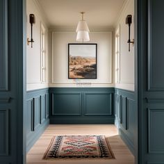 an empty hallway with blue painted walls and wood flooring, framed artwork on the wall